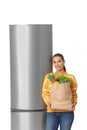 Young woman with bag of groceries near closed refrigerator Royalty Free Stock Photo