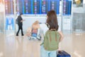 Young woman with bag and luggage checking flight time information board in international airport, before check in. Travel,