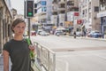 A young woman with a bag is standing at a crossroads at a traffic light