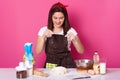 Young woman baker in kitchen, sprinkling white flour on dough, baking delicious coockies, likes homemade pastry, posing isolated