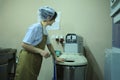 Young woman baker standing near dough mixing machine regulating level of power on a control panel. Brovary, Ukraine