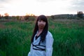 young woman in baldric on the summer field on sunset or sunrise. peaceful calm female. trendy clothes