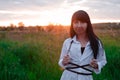 young woman in baldric on the summer field on sunset or sunrise. peaceful calm female. trendy clothes