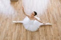 Young woman ballerina in white pack posing on background of wooden floor. Royalty Free Stock Photo