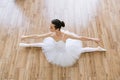 Young woman ballerina in white pack posing on background of wooden floor. Royalty Free Stock Photo