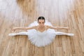 Young woman ballerina in white pack posing on background of wooden floor. Royalty Free Stock Photo