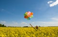 Young woman with balloons on canola field. Royalty Free Stock Photo