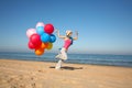 Young woman with balloons running on the beach