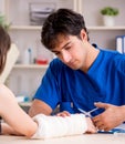 Young woman with bandaged arm visiting male doctor traumotologis Royalty Free Stock Photo