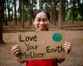 The young woman with banners protesting over pollution and global warming in the forest to save planet earth. The concept of World