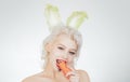 Young woman with banny ears eat carrot. Cute bunny rabbit. Easter bunny dress.