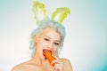 Young woman with banny ears eat carrot. Cute bunny rabbit. Easter bunny dress.