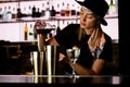 Young woman bartender pours red alcoholic drink into shaker to make cocktail at bar counter Royalty Free Stock Photo