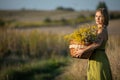 A young woman with a basket full of herbs stands by a dirt road and brews backwards. Common goldenrod and winterberry. Royalty Free Stock Photo