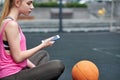 Young woman with basketball uses phone after training. Black screen