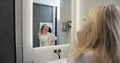 Young woman in bathrobe drying hair with a hairdryer in the bathroom at home. Usual morning beauty treatments in the Royalty Free Stock Photo