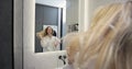 Young woman in bathrobe drying hair with a hairdryer in the bathroom at home. Usual morning beauty treatments in the Royalty Free Stock Photo