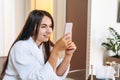 Young woman in bathrobe in hotel room using mobile phone