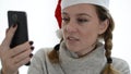 Young woman in the bathroom wearing a santa claus hat talks by video call on a smartphone and drinks champagne congratulating frie