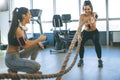 Young woman with battle ropes exercise in the fitness gym witth support from her friends