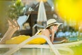 Young woman on beach chair at swimming pool working on computer laptop and talking on sell phone in summer resort. Remote work and Royalty Free Stock Photo