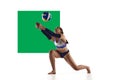 Young woman, beach volleyball player in motion during game, hitting ball over white background with green element. Royalty Free Stock Photo