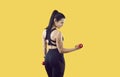 Young woman with beautiful athletic body trains triceps using dumbbells on vivid yellow background. Royalty Free Stock Photo