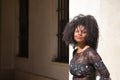 Young woman, beautiful and black with afro hair, with floral dress leaning on a wall, relaxed, quiet and happy. Concept beauty, Royalty Free Stock Photo