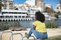 Young woman, beautiful and black with afro hair, with yellow shirt, jeans and boots, sitting on iron bars, looking at infinity, Royalty Free Stock Photo