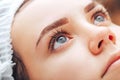 Young woman with beautiful eyebrows after procedure permanent make-up in salon, closeup photo