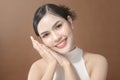 Young woman with beautiful face smiling , touching her face over brown background , beauty skin care concept Royalty Free Stock Photo