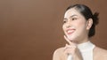 Young woman with beautiful face smiling , touching her face over brown background , beauty skin care concept Royalty Free Stock Photo