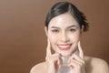 Young woman with beautiful face smiling , touching her face over brown background , beauty skin care concept Royalty Free Stock Photo