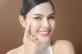 Young woman with beautiful face smiling , touching her face over brown background , beauty skin care concept Royalty Free Stock Photo