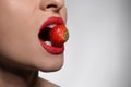 Young woman with beautiful lips makeup eating strawberry on light background, closeup. Space for text Royalty Free Stock Photo