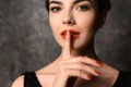 Young woman with beautiful manicure showing silence gesture on dark background Royalty Free Stock Photo