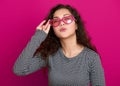 Young woman beautiful portrait make flying kiss, posing on pink background, long curly hair, sunglasses in heart shape, glamour co Royalty Free Stock Photo