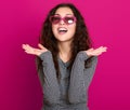 Young woman beautiful portrait, posing on pink background, long curly hair, sunglasses in heart shape, glamour concept Royalty Free Stock Photo