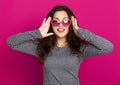 Young woman beautiful portrait, posing on pink background, long curly hair, sunglasses in heart shape, glamour concept Royalty Free Stock Photo