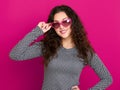 Young woman beautiful portrait, posing on pink background, long curly hair, sunglasses in heart shape, glamour concept Royalty Free Stock Photo