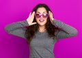 Young woman beautiful portrait, posing on purple background, long curly hair, sunglasses in heart shape, glamour concept Royalty Free Stock Photo