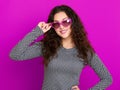 Young woman beautiful portrait, posing on purple background, long curly hair, sunglasses in heart shape, glamour concept Royalty Free Stock Photo