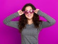 Young woman beautiful portrait, posing on purple background, long curly hair, sunglasses in heart shape, glamour concept Royalty Free Stock Photo