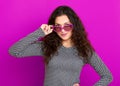 Young woman beautiful portrait, posing on purple background, long curly hair, sunglasses in heart shape, glamour concept Royalty Free Stock Photo