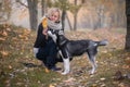 Young woman with beautiful siberian husky dog playing in city park during autumn Royalty Free Stock Photo