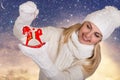 A young woman in beautiful white knitted clothes is holding wooden horse christmas decoration for christmas tree.Merry Christmas Royalty Free Stock Photo