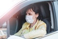 Young woman, beauty in a medical mask driving a car in town, New life in a pandemic Royalty Free Stock Photo