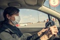 Young woman, beauty in a medical mask driving a car in town, New life in a pandemic Royalty Free Stock Photo