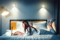 Young woman in bed using laptop. Girl works on Internet, browsing social media or chatting on video call Royalty Free Stock Photo