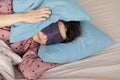 young woman in bed wakes up, insomnia, sleep disorder. person in sleep mask holds onto pillows Royalty Free Stock Photo